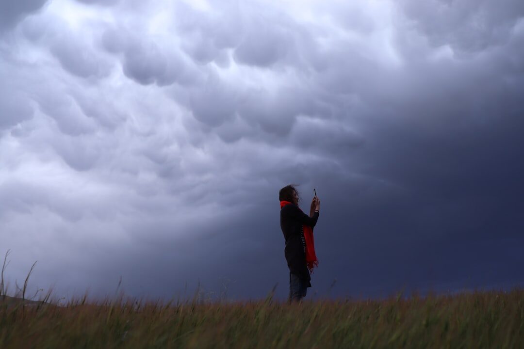 Reporter presenting a live weather cross outdoors under a stormy sky