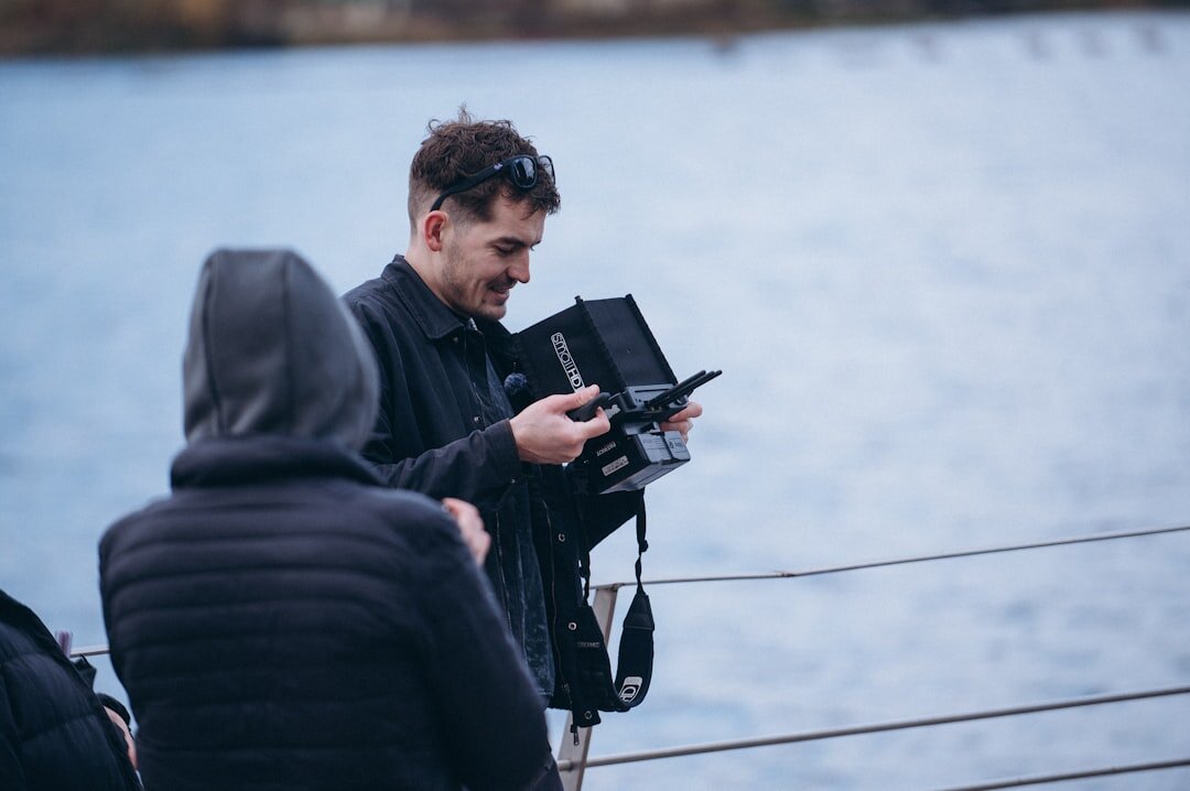 Camera operator scouting an outdoor broadcast location with a tripod and camera